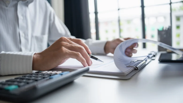 A CFO reviewing a 13-week cash flow model with a calculator and printed ledger