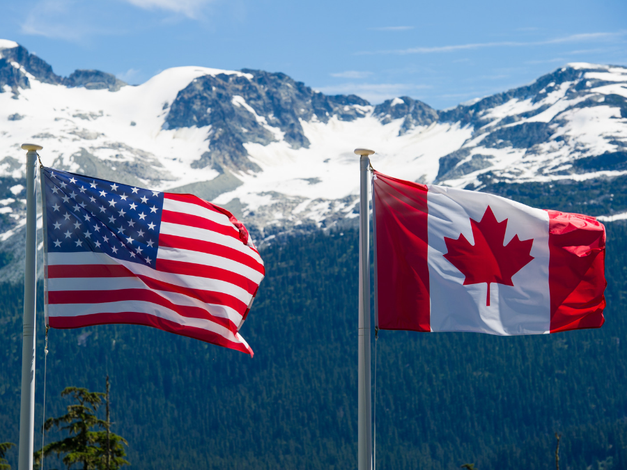 US and Canadian flags flying together with mountains in the background
